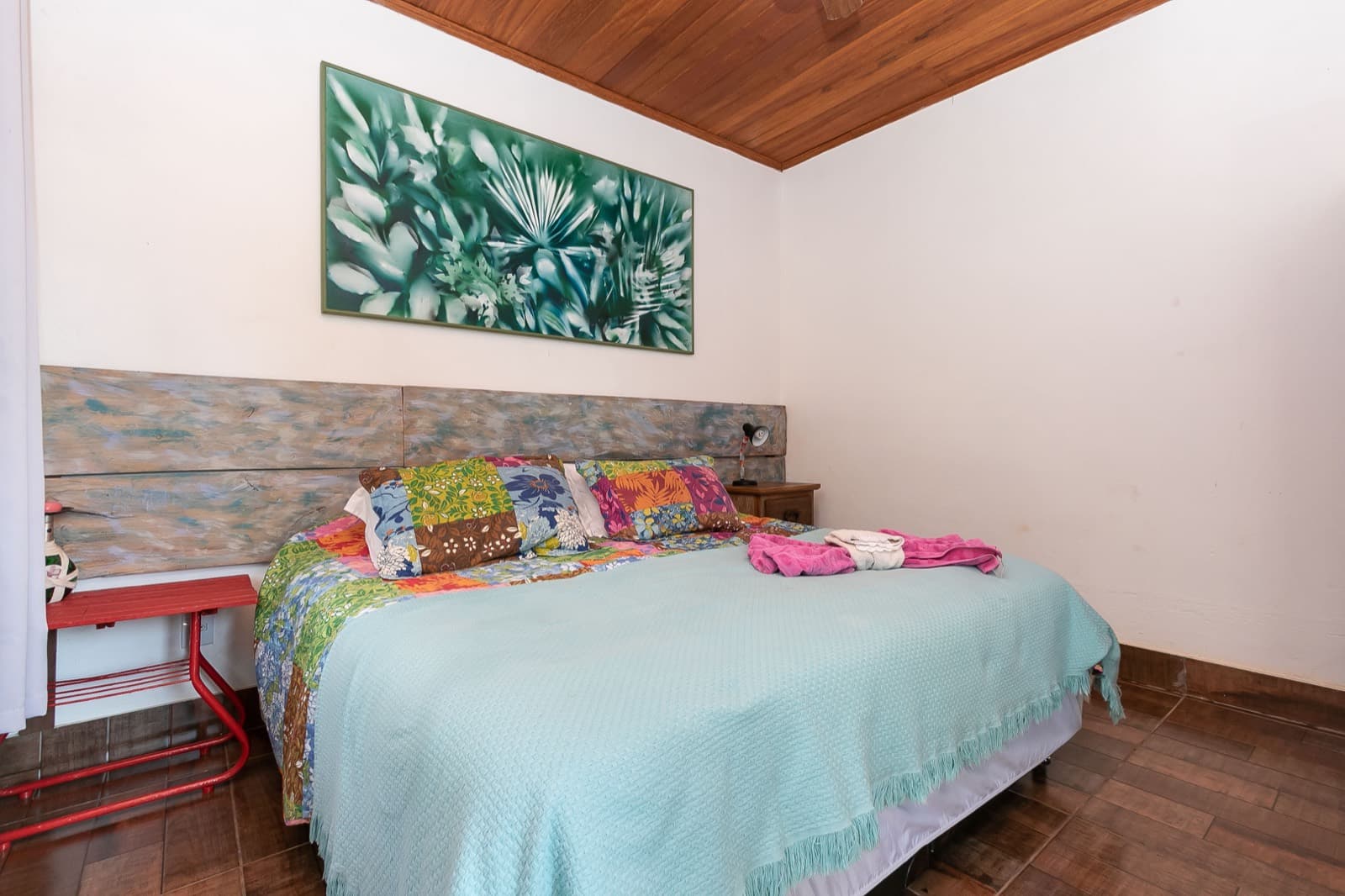 Suíte 2, clara, com quadro de folhagens sobre a cama
