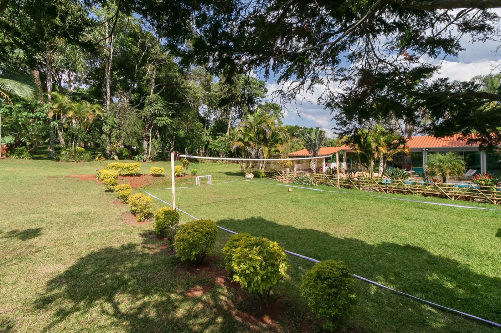 Campo gramado com rede de vôlei e trave